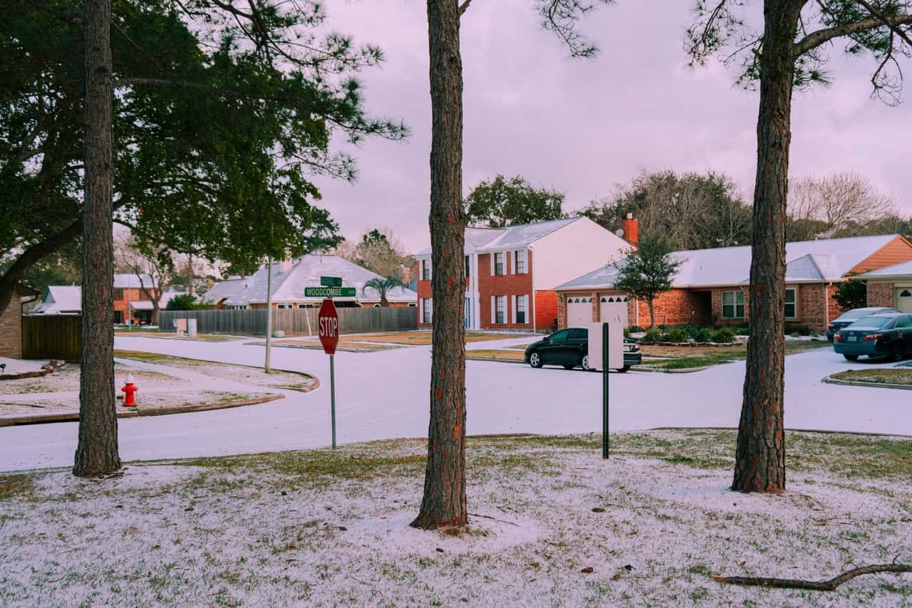 Light snow on trees and lawns in a neighborhood of brick houses