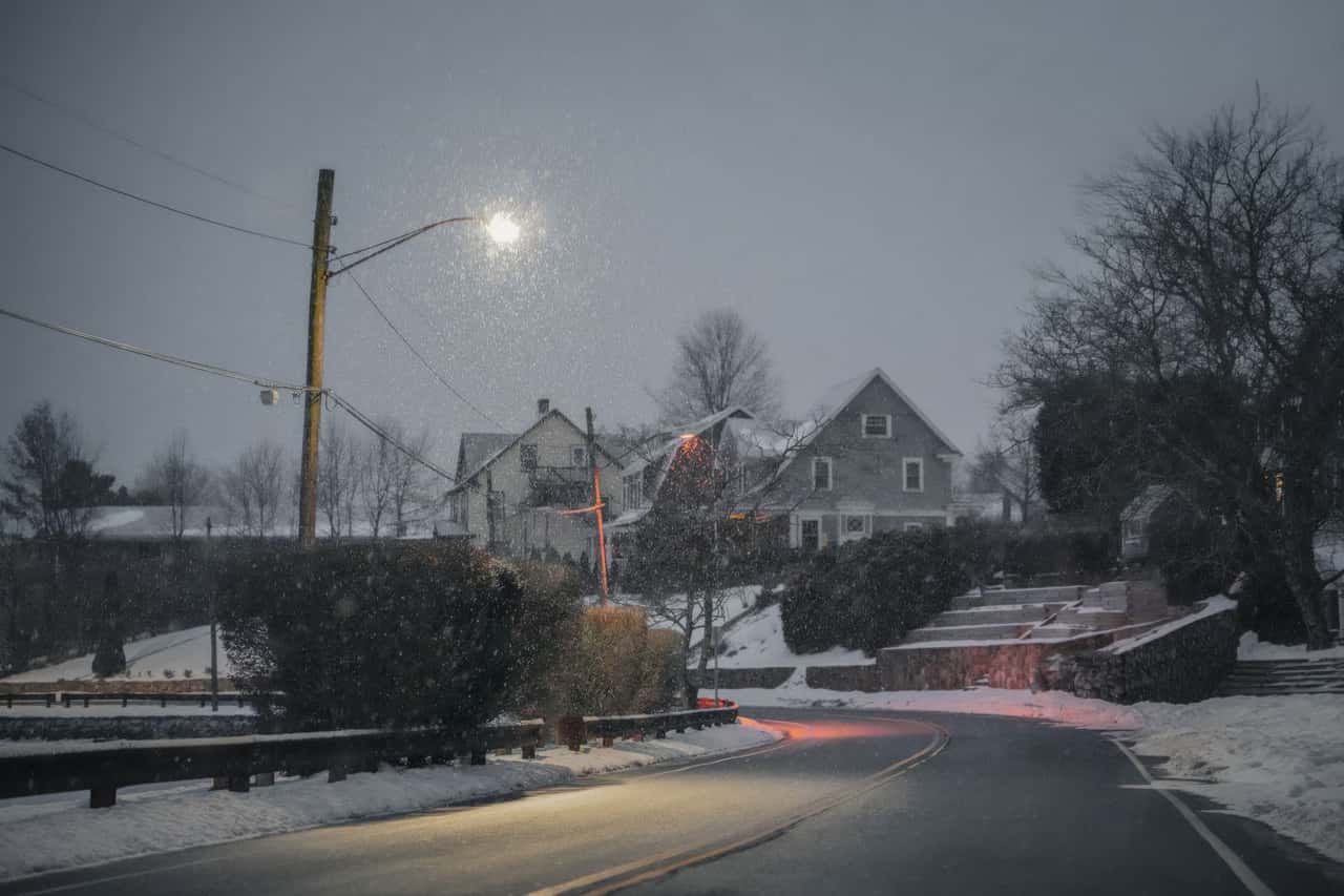 Residential street after snowfall, with bare trees and overhead lines
